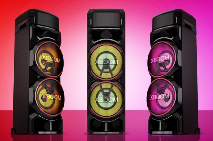 LG XBOOM RNC9 speaker showcasing multicolor lighting effects, positioned in a lively party setting with people dancing and music playing.