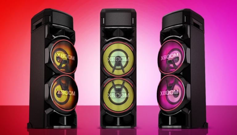 LG XBOOM RNC9 speaker showcasing multicolor lighting effects, positioned in a lively party setting with people dancing and music playing.